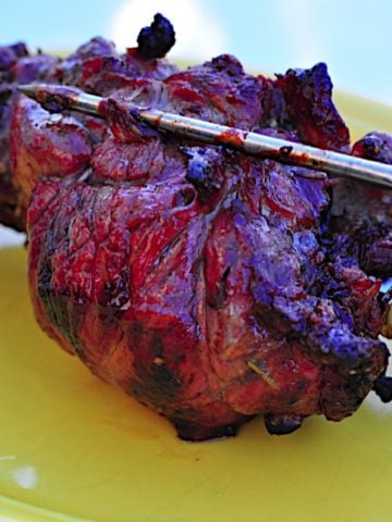 A rotisserie lamb shoulder roast, still on the rotisserie spit