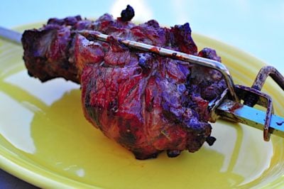 A rotisserie lamb shoulder roast, still on the rotisserie spit