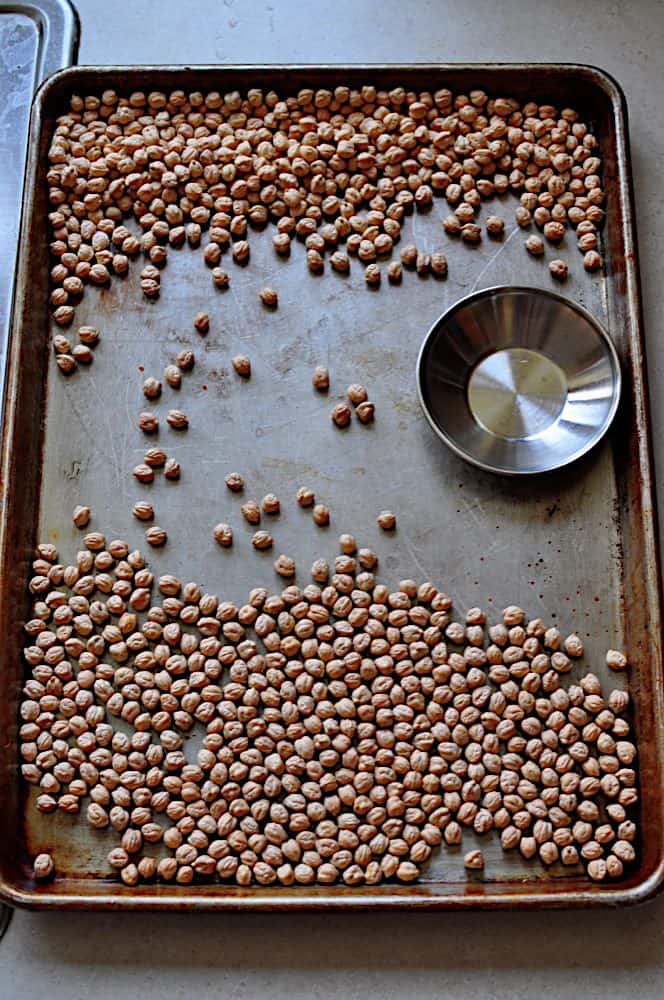 Sorting chickpeas in a sheet pan with dried chickpeas and a small dish to hold any stones