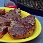 A plate of grilled lamb loin chops with a grill in the background