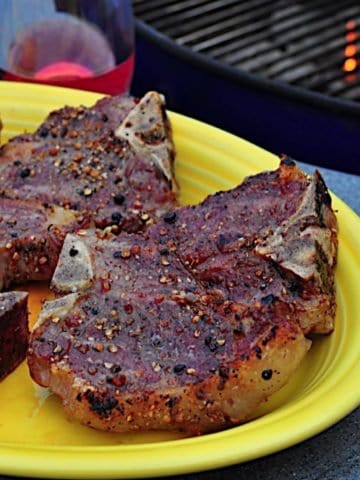 A plate of grilled lamb loin chops with a grill in the background