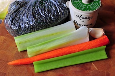 Trimmed celery, carrot, and leeks, with a bag of French lentils du Puy and a crock of herbes de Provence