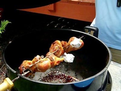 Turkey legs on a rotisserie spit in a kettle grill