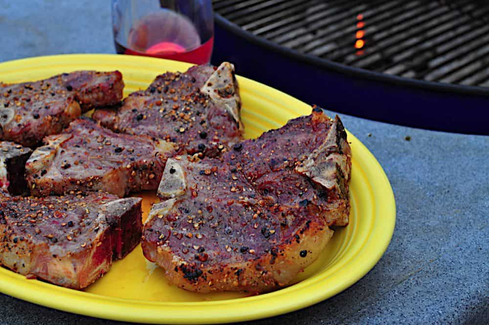 A plate of grilled lamb loin chops with a grill in the background