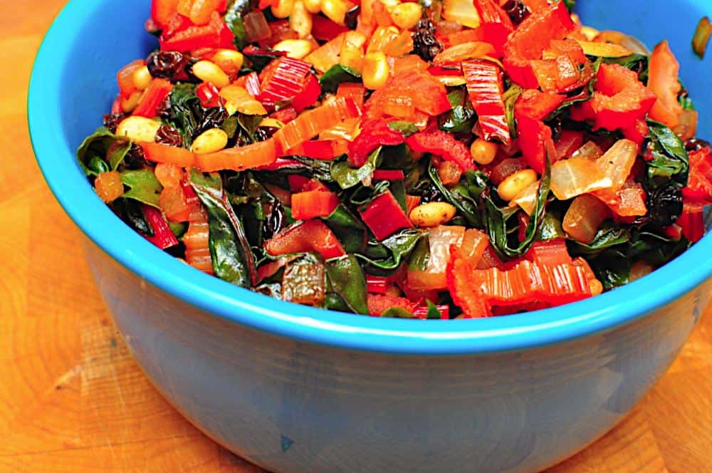 A blue bowl of multicolored cooked and chopped Swiss Chard | Swiss Chard Sautéed With Pine Nuts and Raisins