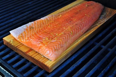 Cedar plank and uncooked salmon filet on the grill