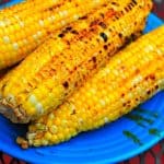 Grilled corn stacked on a blue plate