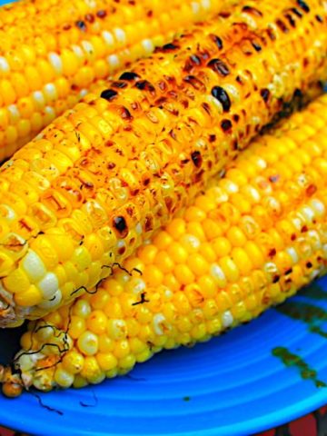 Grilled corn stacked on a blue plate