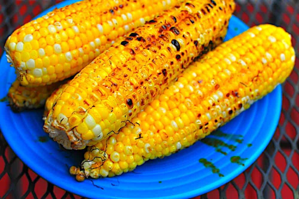 Grilled corn stacked on a blue plate