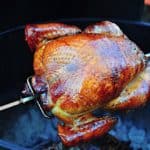 A turkey on the rotisserie over a charcoal grill