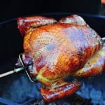 A turkey on the rotisserie over a charcoal grill