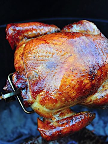 A turkey on the rotisserie over a charcoal grill