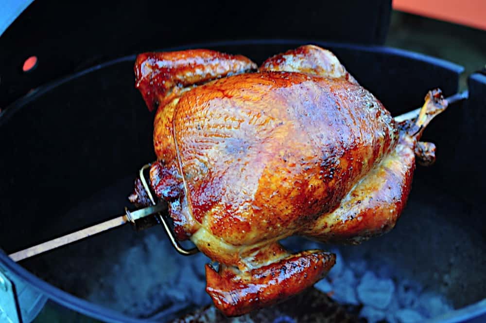 A turkey on the rotisserie over a charcoal grill