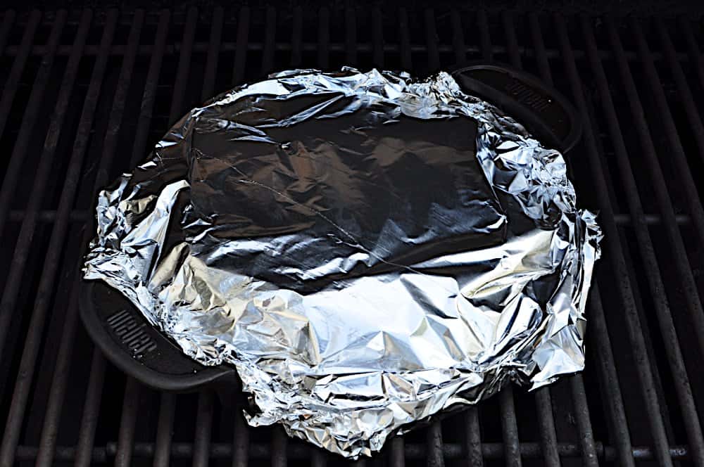 Foil covered pan of brats on the grill over medium heat