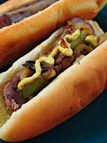 A plate of brats with peppers and onions