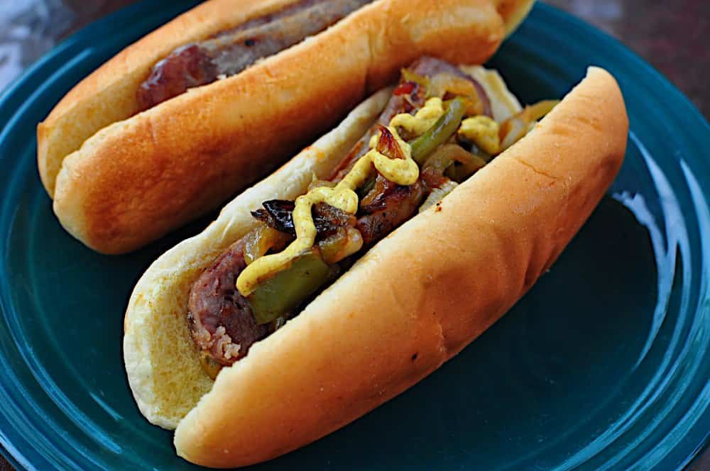 A plate of brats with peppers and onions