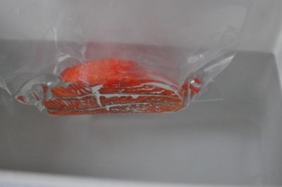 Lowering a zip top bag of salmon into a beer cooler full of hot water