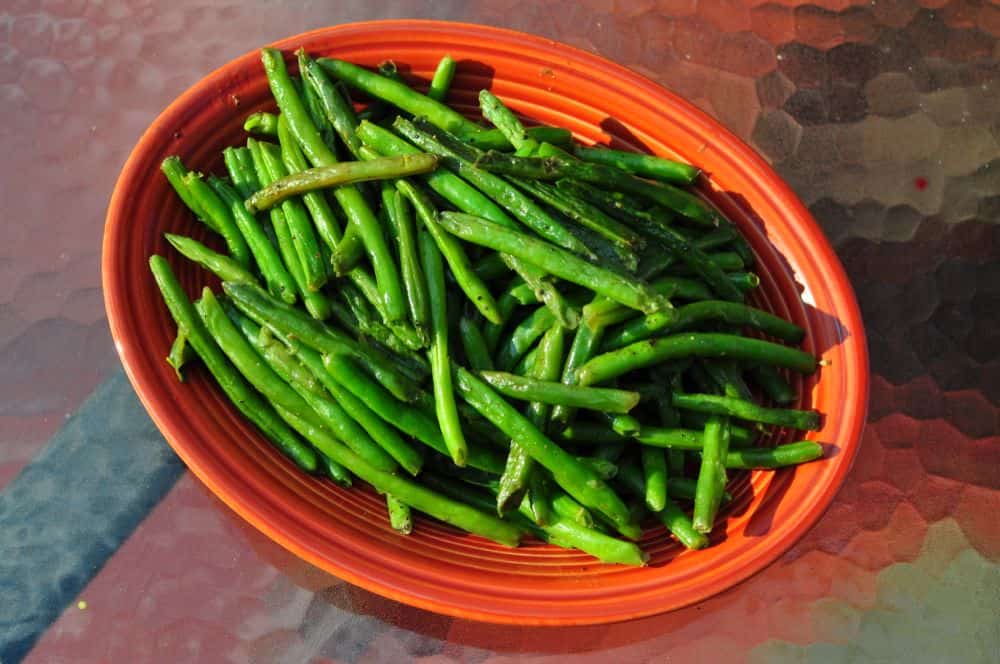 A platter of grilled green beans on the patio table.