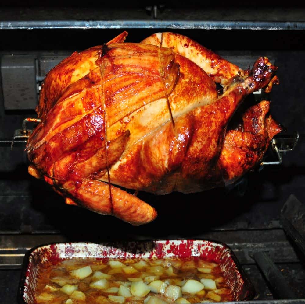 Rotisserie turkey with bacon, browned and ready to take off the grill