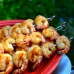Grilled shrimp skewers on a red platter