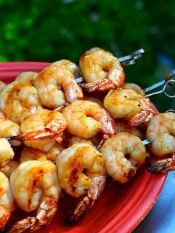 Grilled shrimp skewers on a red platter