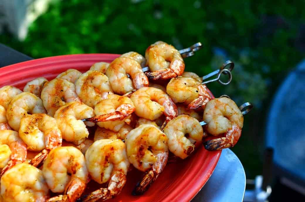 Grilled shrimp skewers on a red platter