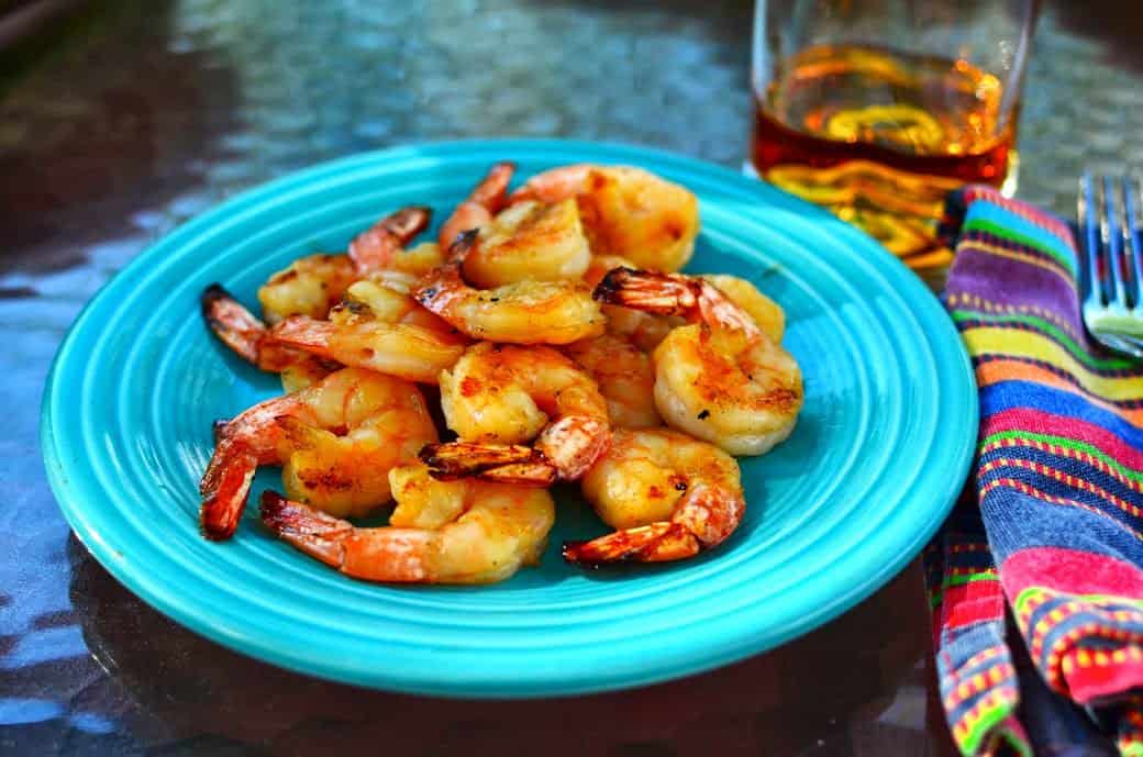 A plate of grilled shrimp, with a glass of Knob Creek bourbon