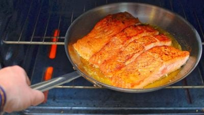 Frypan of seared salmon going into the oven to roast