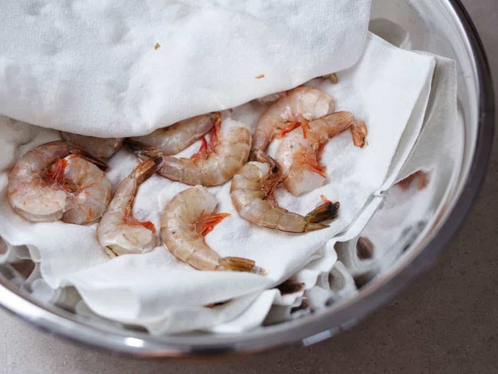 A bowl of raw shrimp between two paper towels