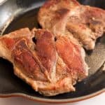 Sous Vide Pork Shoulder steaks searing in a cast iron fry pan