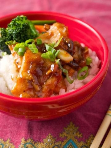 A bowl of velveted chicken stir fry on rice, with chopsticks