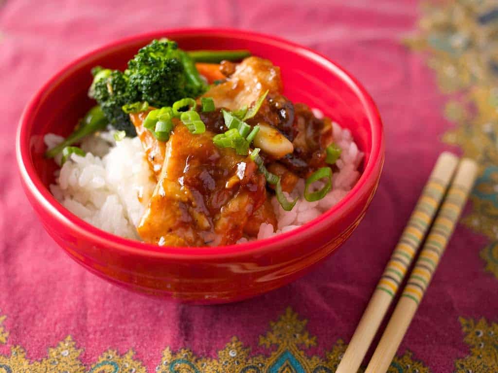 A bowl of velveted chicken stir fry on rice, with chopsticks