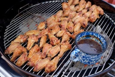 Chicken wings grilling over indirect heat while the sauce simmers over the coals