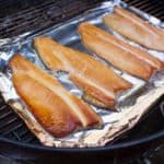 Smoked trout on a piece of aluminum foil in a grill