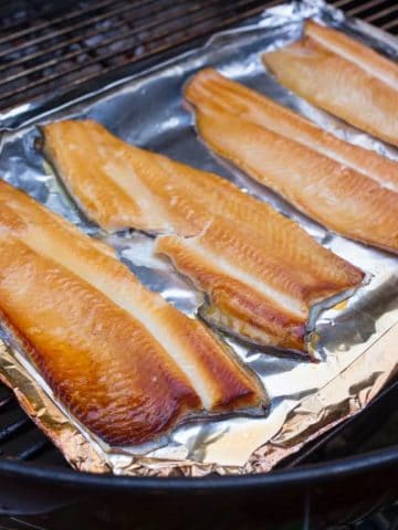 Smoked trout on a piece of aluminum foil in a grill