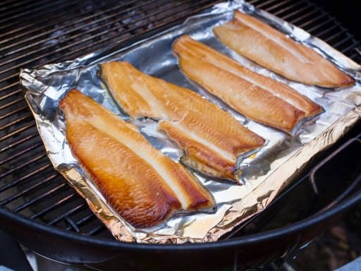 Smoked trout on a piece of aluminum foil in a grill