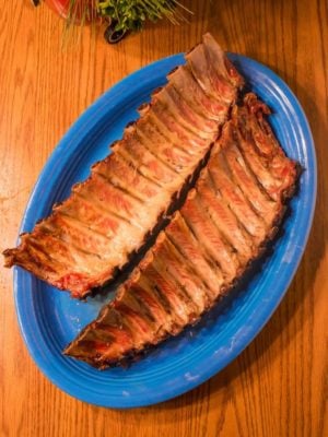 Two racks of baby back ribs on a large blue serving platter