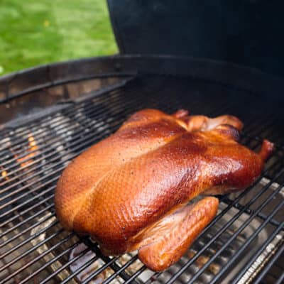 Browned duck on a grill, with coals behind it