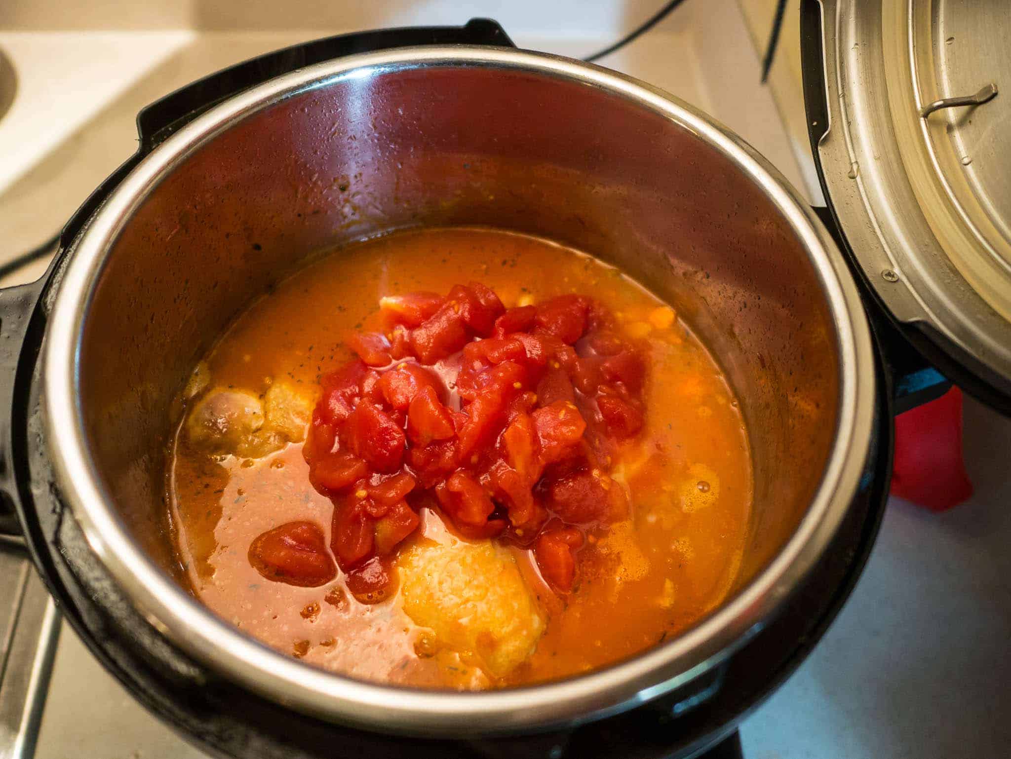 Instant Pot full of chicken, broth, and tomatoes