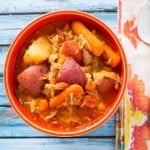 A bowl of chicken stew on a blue wood table