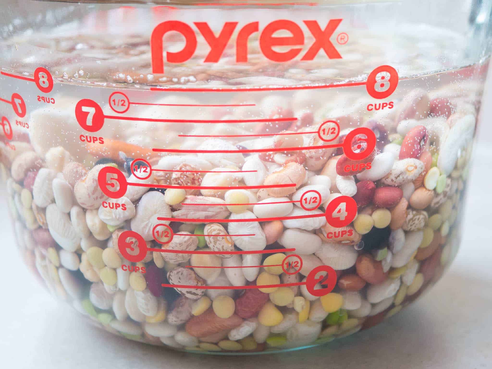 A pyrex bowl of beans covered in water