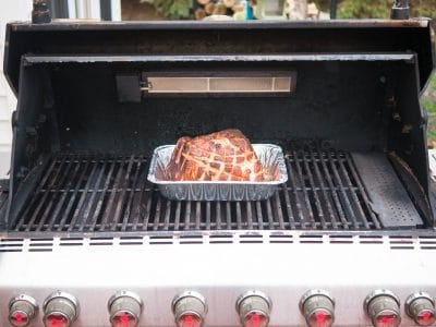 On the grill - lit burners on the sides, ham in the middle