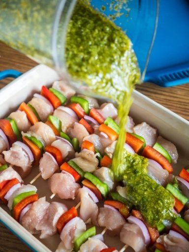 Pouring salsa verde onto the kebabs - Grilled Chicken Kebabs With Italian Salsa Verde | DadCooksDinner.com
