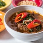 A bowl of panang curry topped with sliced basil and hot peppers