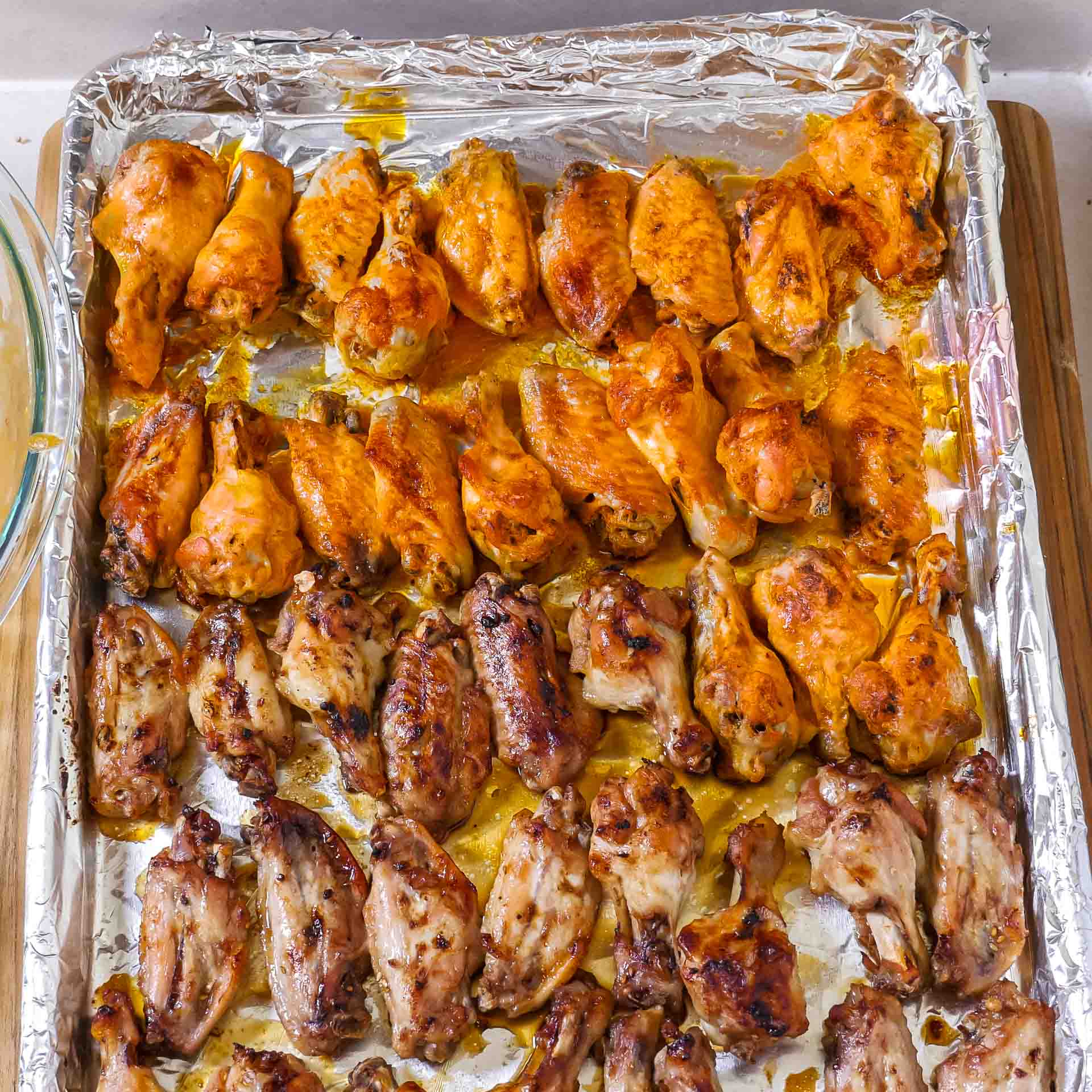 Chicken wings sauced and on a baking sheet to broil