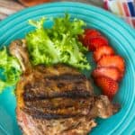 A sous vide duck leg with grill marks on a plate with strawberries and lettuce