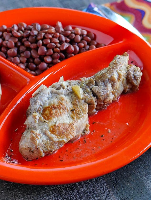 A plate with a country style rib and some beans