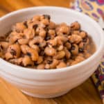 A bowl of cooked black-eyed peas on a wooden tabletop