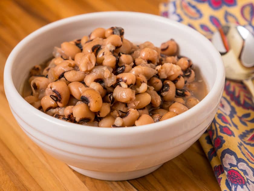 A bowl of cooked black-eyed peas on a wooden tabletop