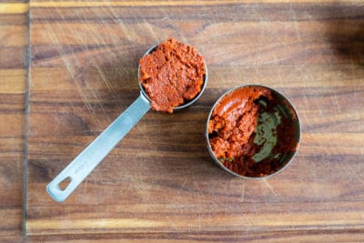 Quarter cup measure full of curry paste next to a half-full jar of curry paste